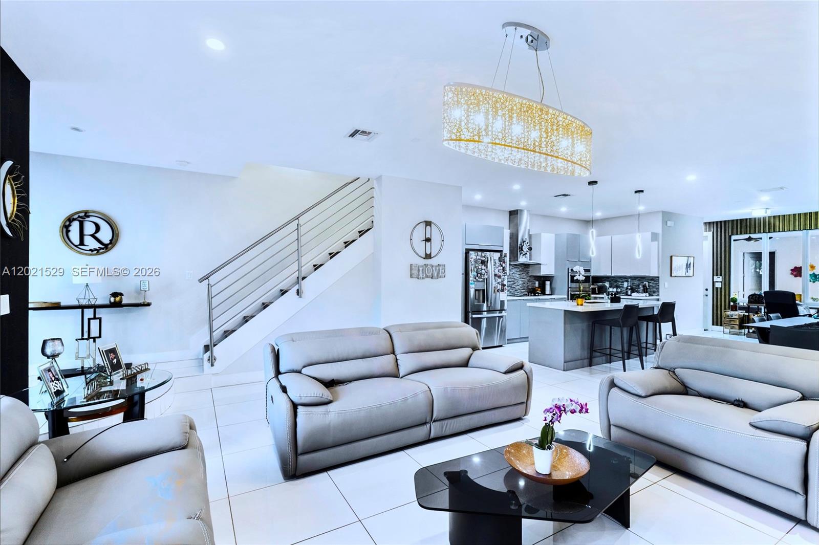 A modern open-concept living room features light gray sofas, tile flooring, and a kitchen island — 6400 NW 105th Pl, Doral FL 33178, DORAL, FL