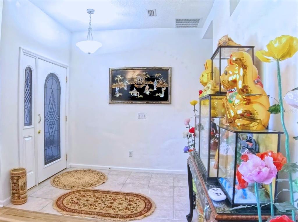 An entryway features tile flooring, a decorative wall hanging, and a glass display case — 5340 NW 26TH LANE, OCALA, FL
