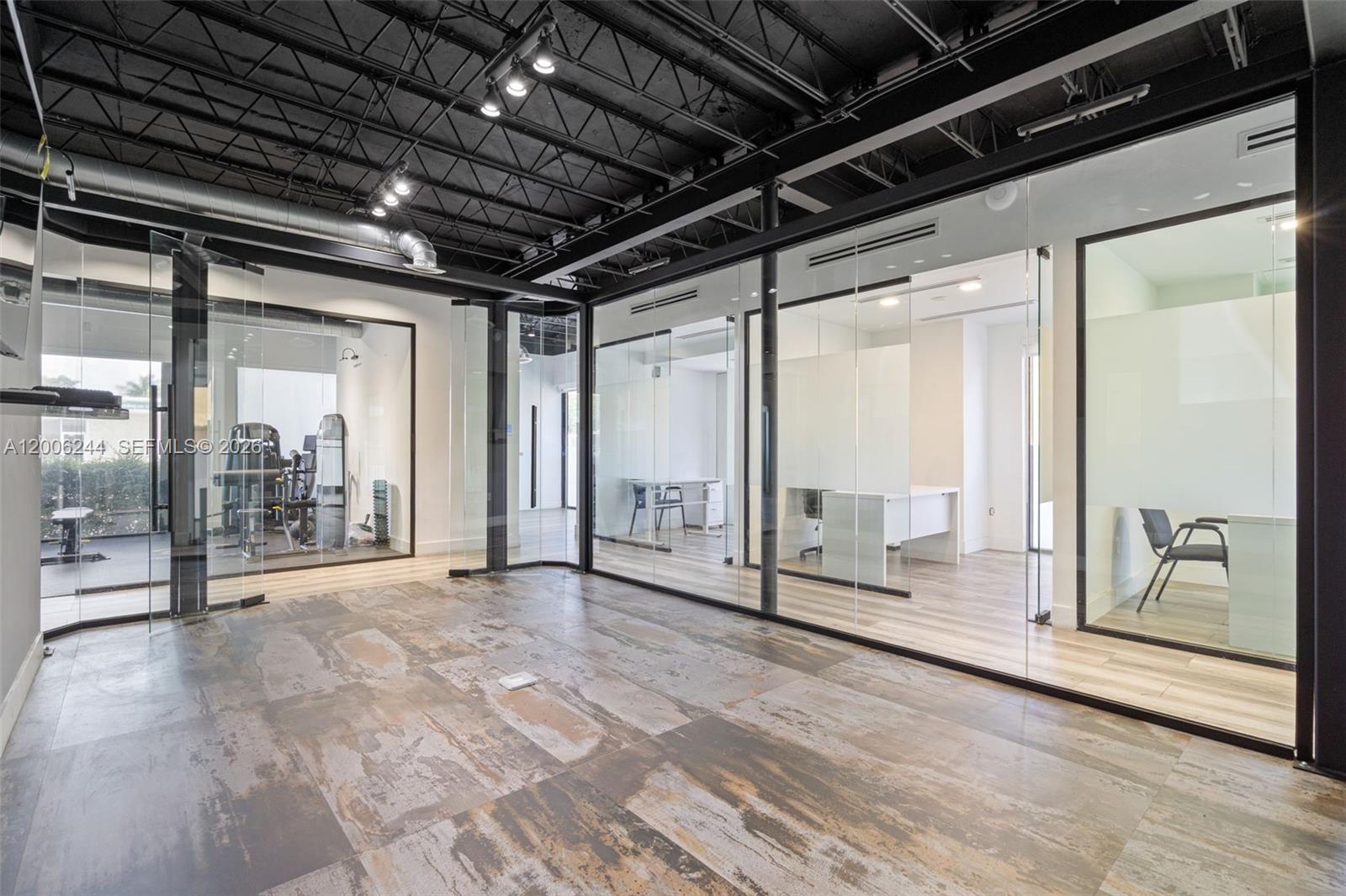 An office space features glass-walled rooms, a dark exposed ceiling, and rustic tile flooring — 4885 NW 7th Ave, Miami FL 33127, MIAMI, FL