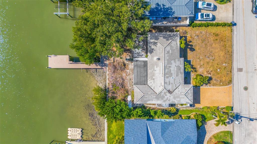 An aerial view shows a waterfront house with a dock, trees, and a paved driveway — 7932 2ND AVENUE S, ST PETERSBURG, FL