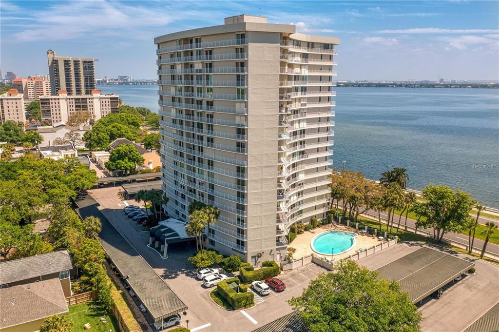 An aerial view shows a tall residential building with a pool and parking lot — 2611 BAYSHORE BOULEVARD UNIT 303, TAMPA, FL