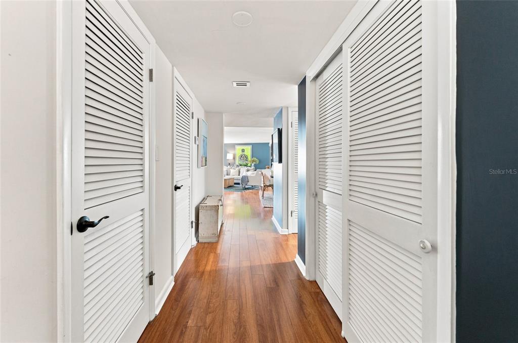 A hallway with wood flooring features white louvered closet doors on both sides — 2611 BAYSHORE BOULEVARD UNIT 303, TAMPA, FL