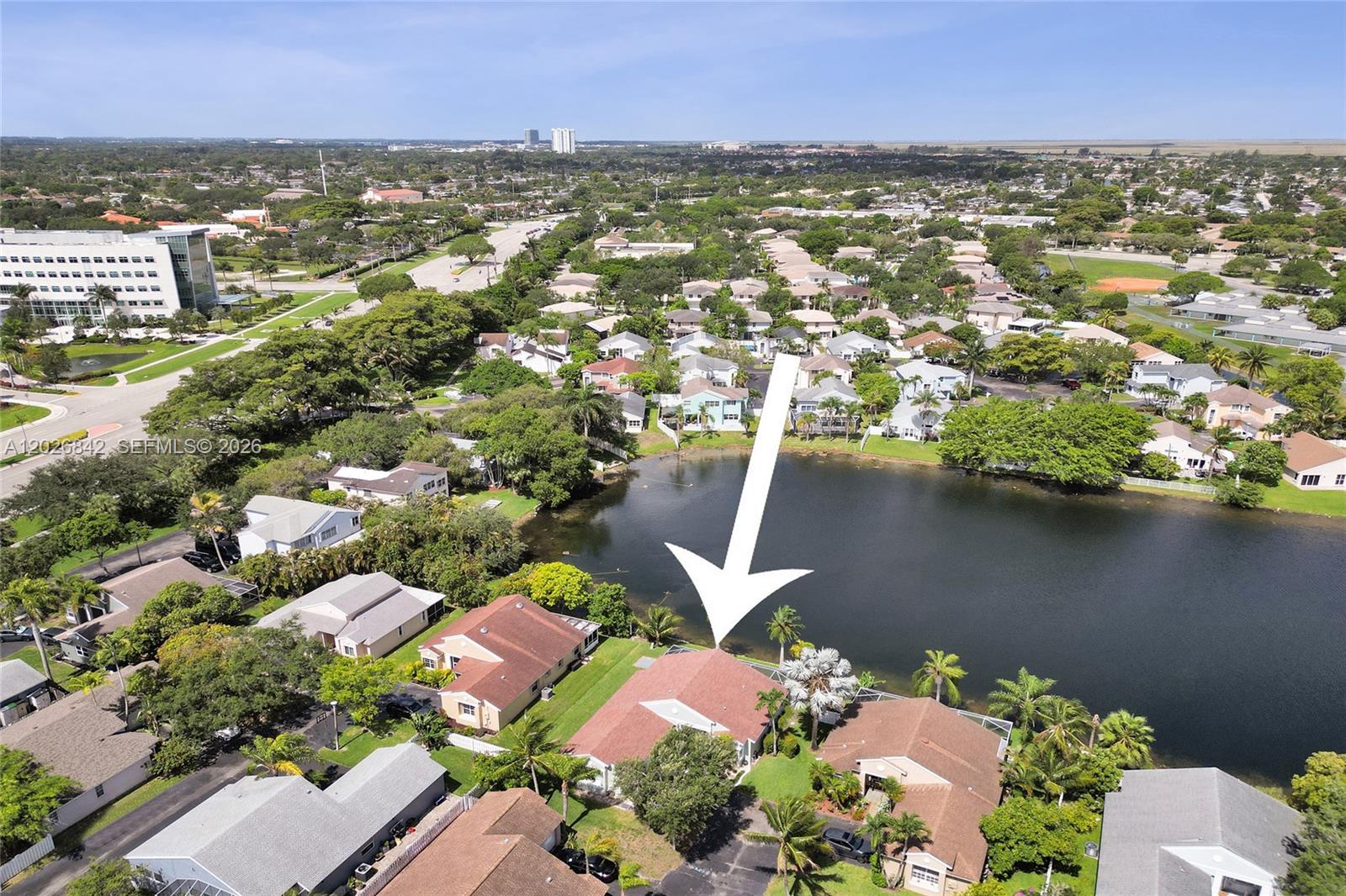 An aerial view shows a residential house with a red roof situated beside a lake — 10639 Lago Welleby Dr, Sunrise FL 33351, SUNRISE, FL