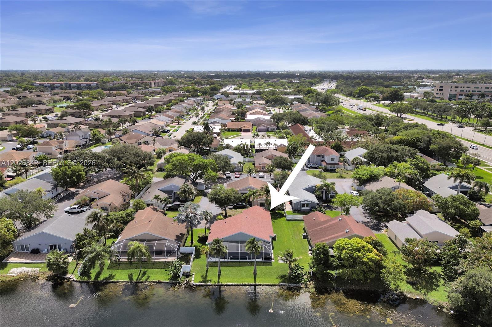 An aerial view shows a residential neighborhood with houses situated along a waterfront — 10639 Lago Welleby Dr, Sunrise FL 33351, SUNRISE, FL