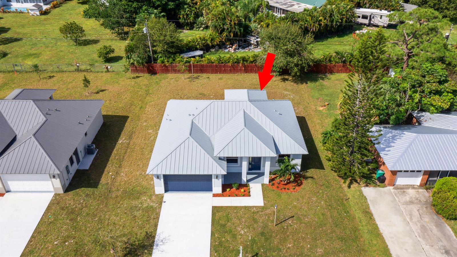 An aerial view shows a single-story house with a gray metal roof and driveway — 4709 Seagrape Drive, Fort Pierce FL 34945, FORT PIERCE, FL