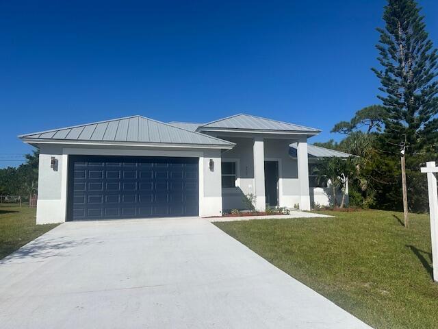 A single-story house with a metal roof, dark garage door, and light-colored exterior walls — 4709 Seagrape Drive, Fort Pierce FL 34945, FORT PIERCE, FL