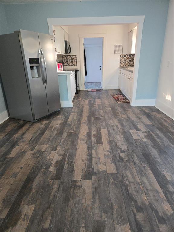 A kitchen features stainless steel appliances, white cabinetry, patterned backsplashes, and dark wood-look flooring — 1034 16TH AVENUE S, ST PETERSBURG, FL