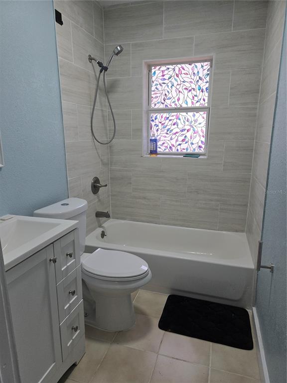 A bathroom features a white vanity, a toilet, and a tub with light-colored tile walls — 1034 16TH AVENUE S, ST PETERSBURG, FL