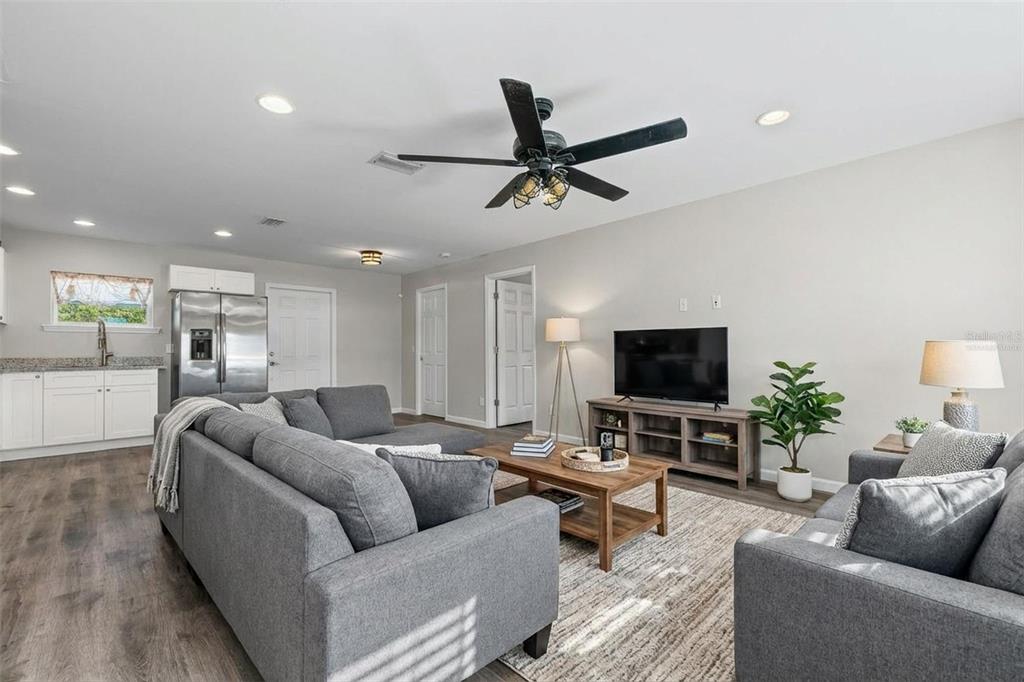 A living room features gray sofas, a wood coffee table, and a television on a console — 18386 LOCKLANE AVENUE, PORT CHARLOTTE, FL
