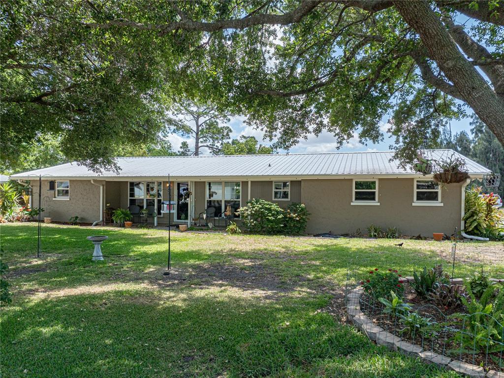 The exterior of a single-story house with a metal roof sits on a grassy lawn — 246 CANAL DRIVE, LAKE WALES, FL