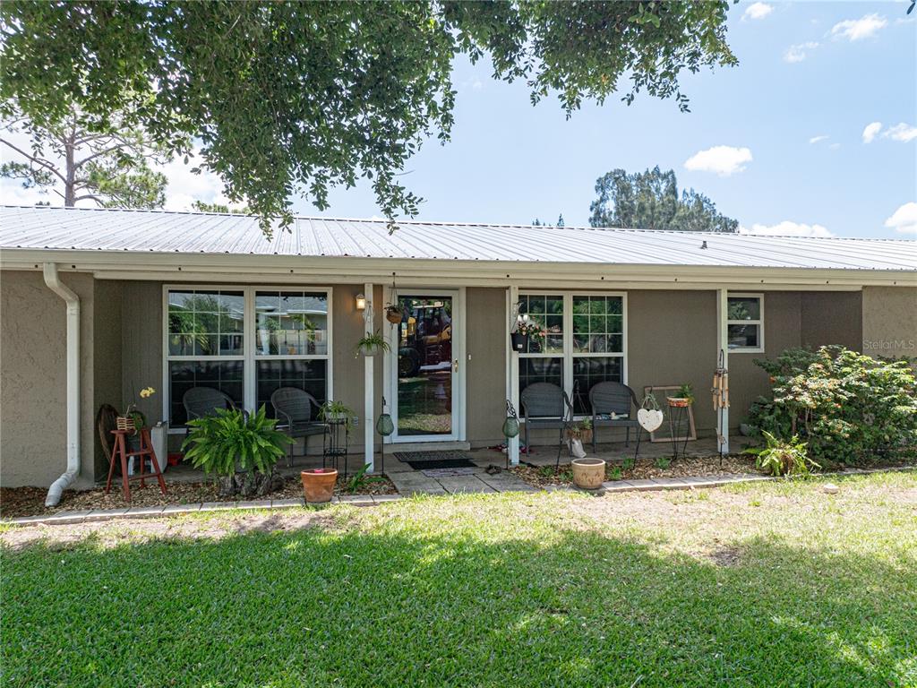 The exterior of a single-story house features a metal roof, a front porch, and large windows — 246 CANAL DRIVE, LAKE WALES, FL