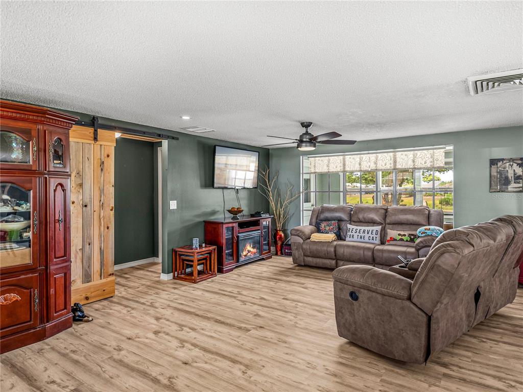 A living room features wood-look flooring, a fireplace console, and a brown reclining sofa — 246 CANAL DRIVE, LAKE WALES, FL