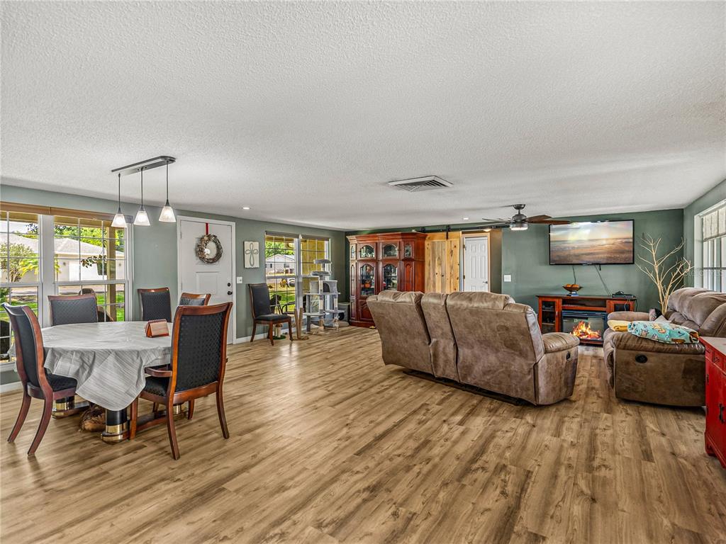 A living and dining area features wood-look flooring, a fireplace, and a ceiling fan — 246 CANAL DRIVE, LAKE WALES, FL