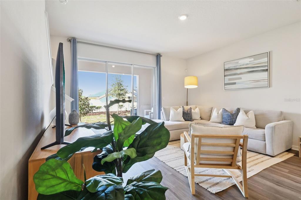 A living room features a sectional sofa, an accent chair, and sliding glass doors — 2618 OLYMPIC COURT, DAVENPORT, FL