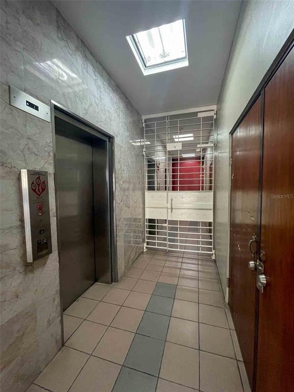 A hallway features a metal elevator, a security gate, tiled floors, and a skylight — 1760 CALLE LOIZA UNIT 803, SAN JUAN, PR