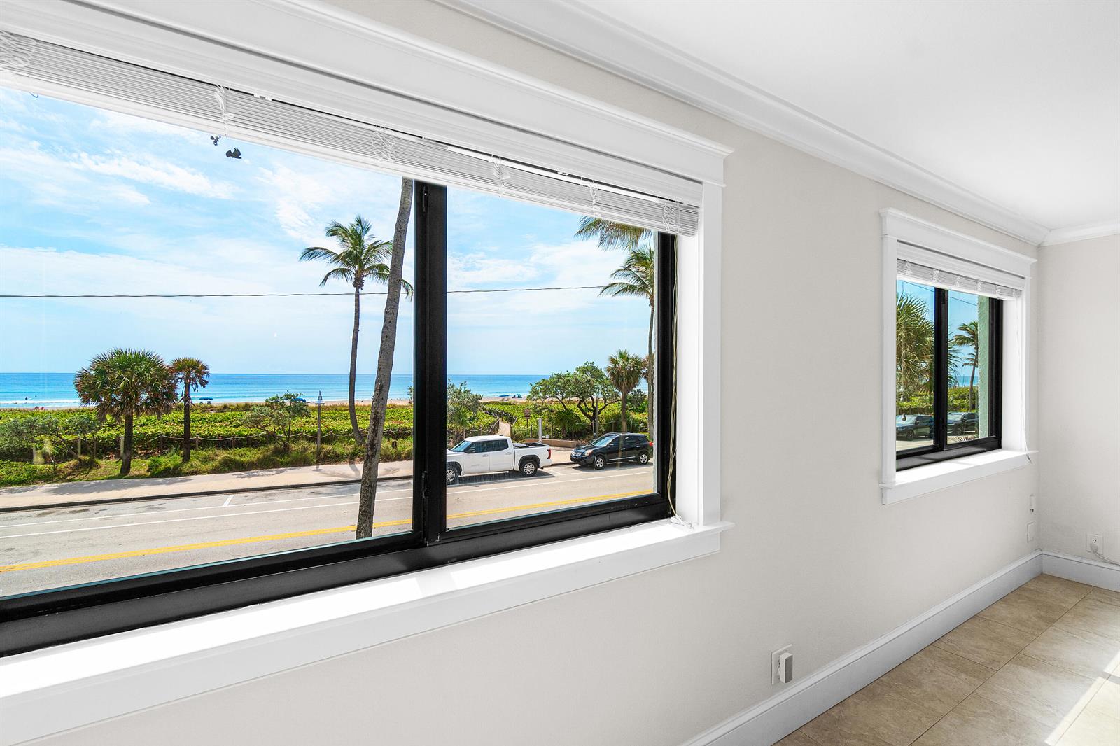 A room with light-colored walls and tile floors features two windows overlooking a beach — 250 S Ocean Boulevard # 253, Delray Beach FL 33483, DELRAY BEACH, FL