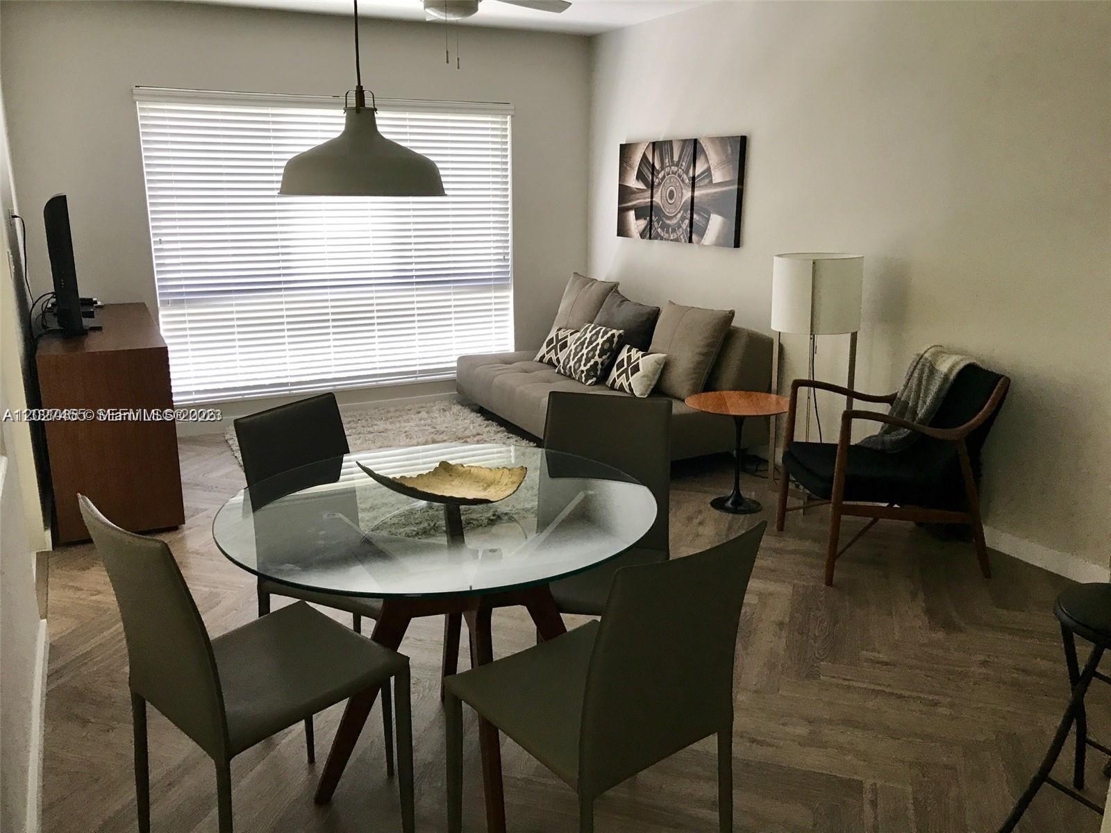A dining area with a glass table and chairs sits in front of a living room — 9920 Collins Ave # 1, Bal Harbour FL 33154, BAL HARBOUR, FL