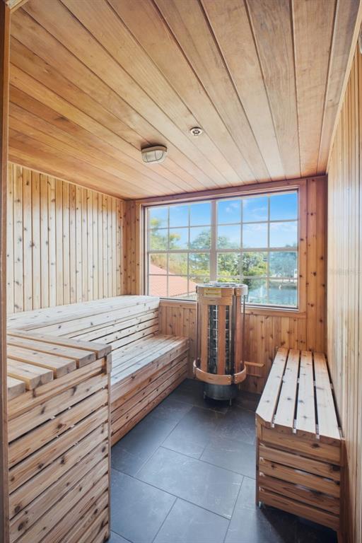 A cedar-lined sauna features wooden benches, a metal heater, and a window overlooking a lake — 2400 FEATHER SOUND DRIVE UNIT 236, CLEARWATER, FL