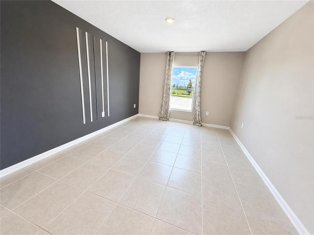 An empty room features light tile flooring, beige walls, and a dark accent wall — 2862 PENNACHIO DRIVE, LAKE WALES, FL