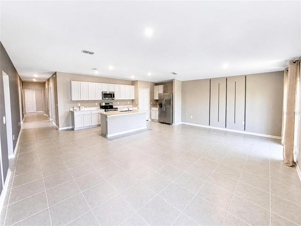 A spacious kitchen with white cabinets and a center island opens into a large living area — 2862 PENNACHIO DRIVE, LAKE WALES, FL