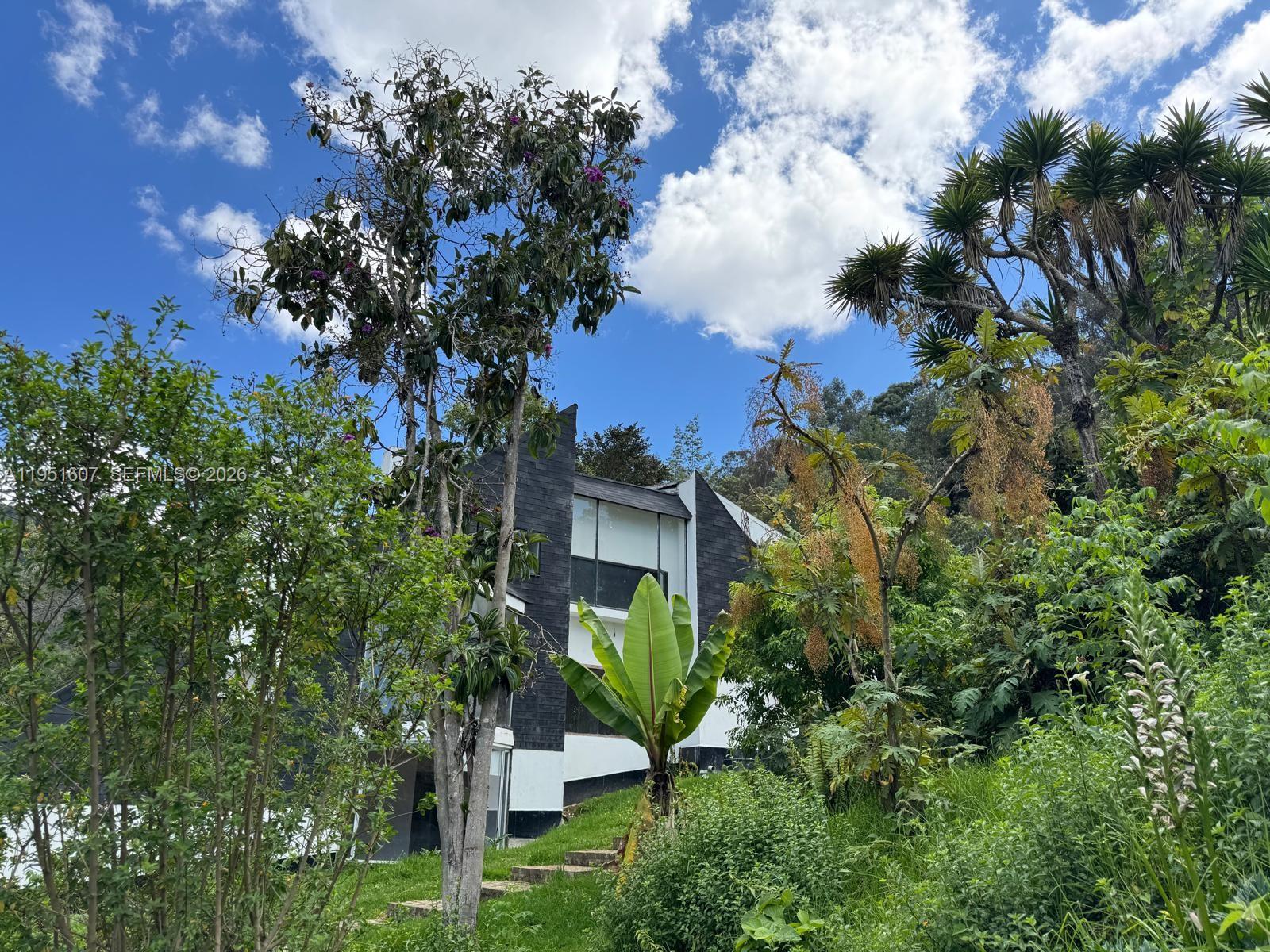 A modern two-story house with black and white exterior walls sits on a grassy hillside — Floresta de la Sabana Floresta de la Sabana, FL