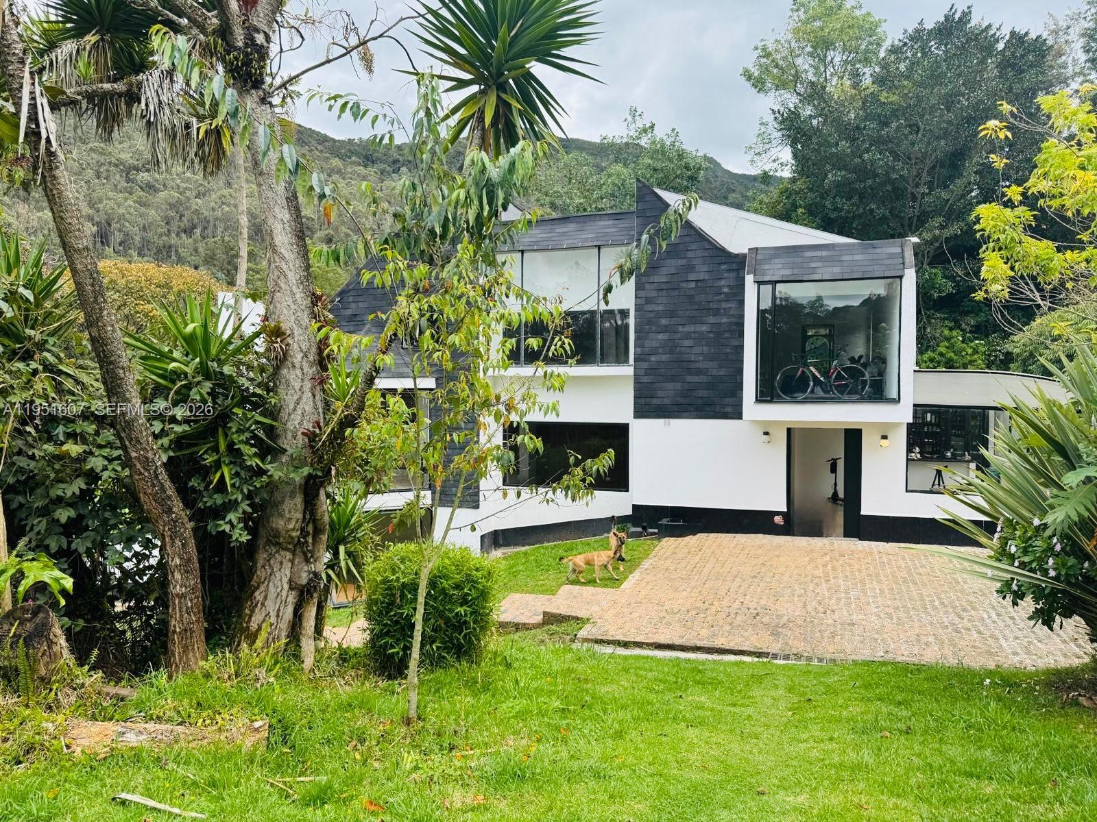 A modern two-story house with black shingle siding and white walls sits on a grassy lot — Floresta de la Sabana Floresta de la Sabana, FL