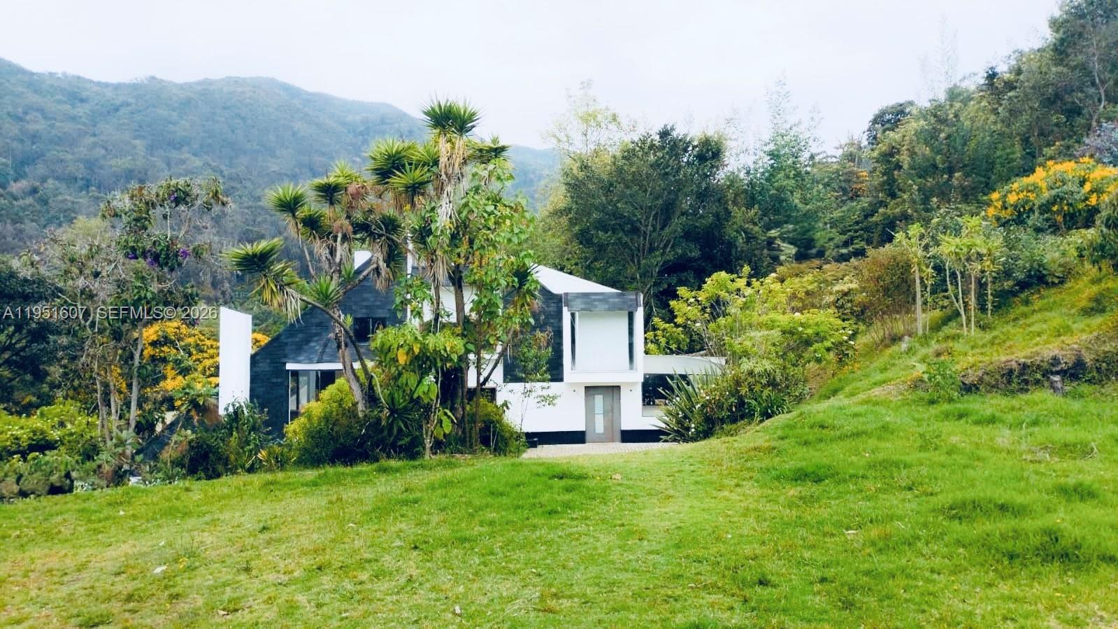 A modern two-story house with white and dark gray exterior walls sits on a grassy hill — Floresta de la Sabana Floresta de la Sabana, FL