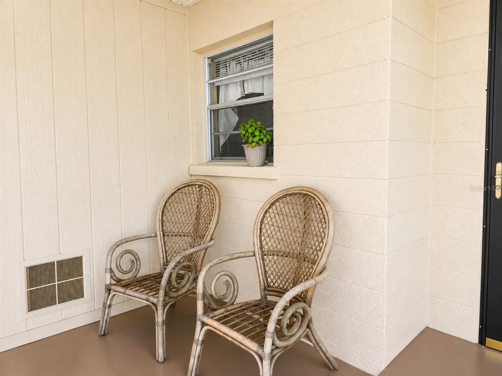 A dark blue front door with a glass storm door sits on a beige porch — 617 PARK CIRCLE UNIT 26, BRADENTON, FL