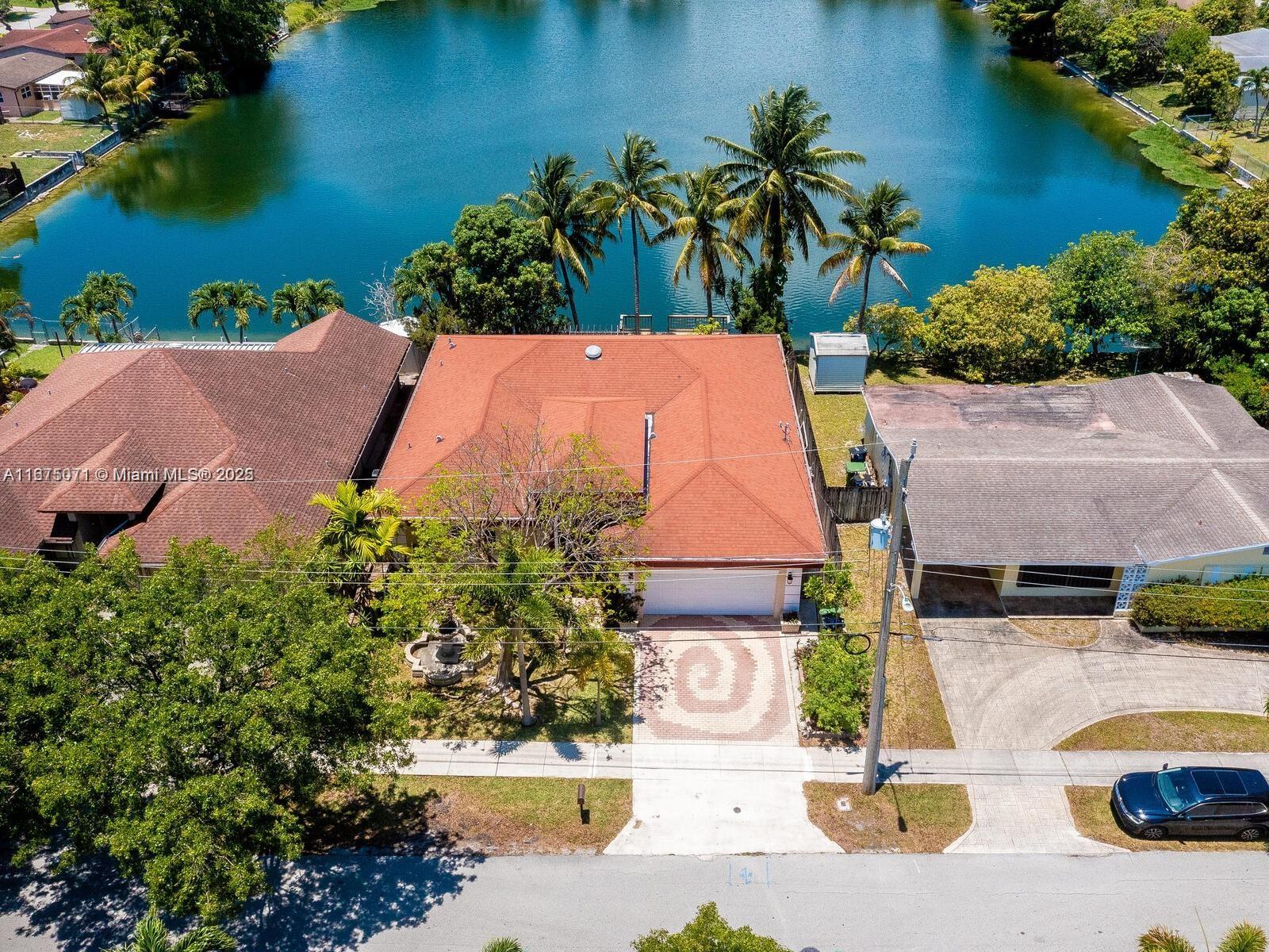 An aerial view shows a house with a red roof situated between two neighbors by water — 232 SW 7th Ave, Hallandale Beach FL 33009, HALLANDALE BEACH, FL