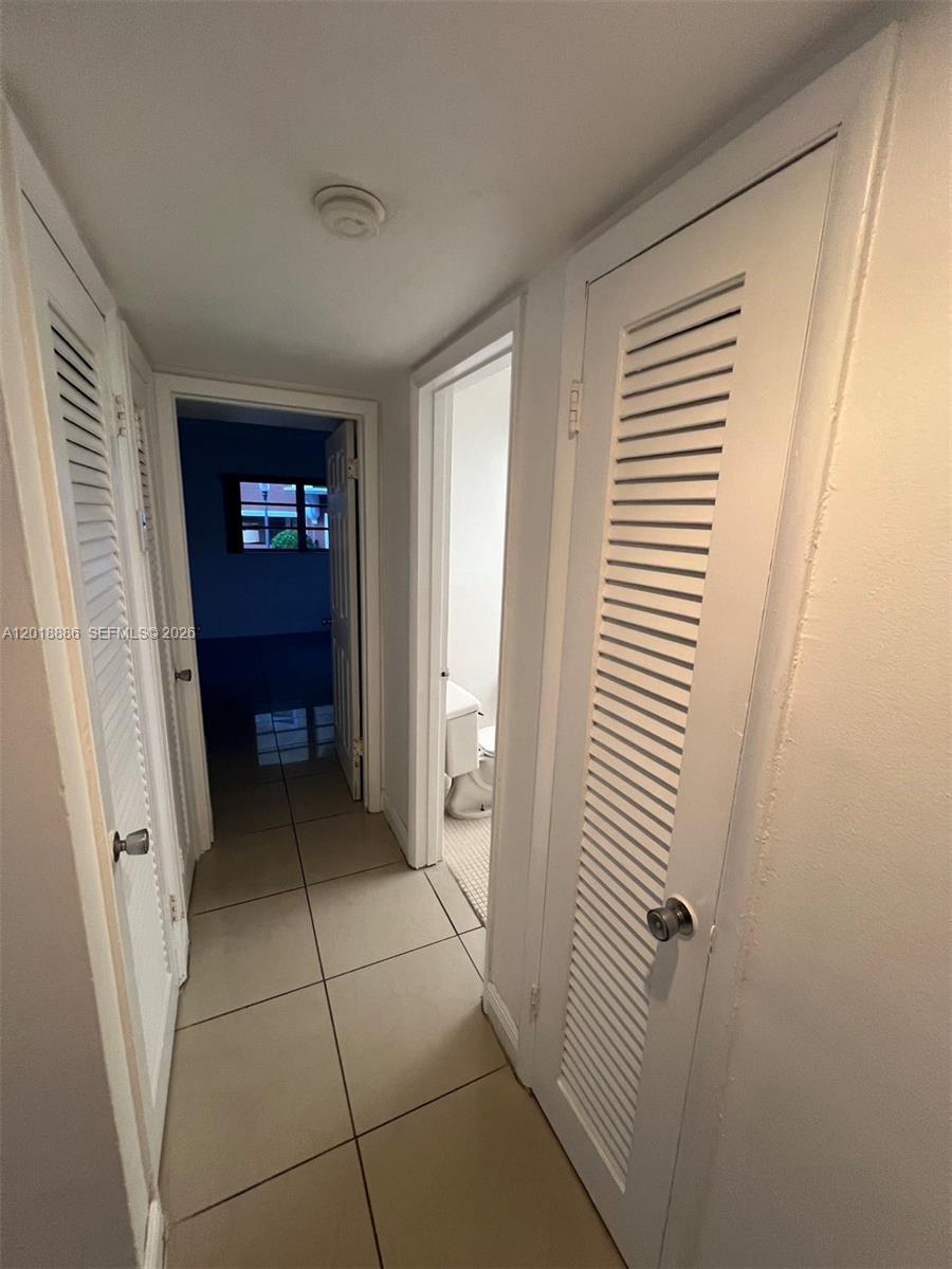 A hallway with tiled floors leads to a bathroom and a bedroom — 7324 SW 82nd St # B210, Miami FL 33143, MIAMI, FL