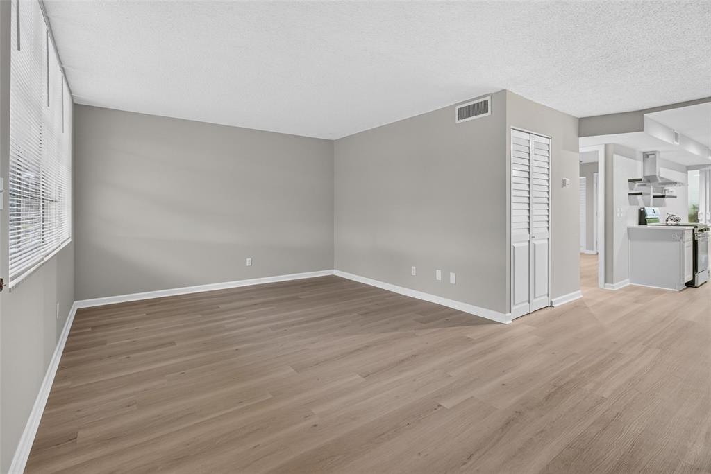 An empty living room features light gray walls, wood-look flooring, and a white louvered closet door — 4885 1ST STREET NE UNIT 109, ST PETERSBURG, FL