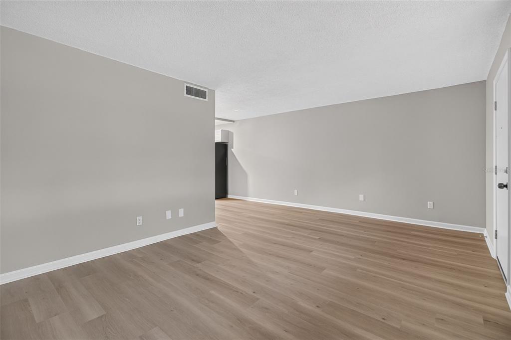 An empty room with light gray walls, wood-look flooring, and a white door — 4885 1ST STREET NE UNIT 109, ST PETERSBURG, FL
