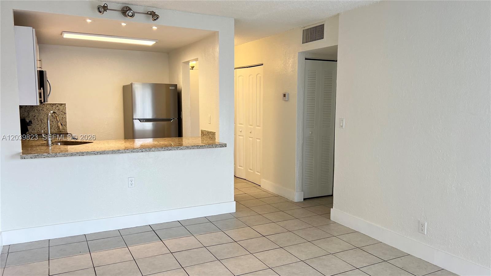 A kitchen with granite countertops and stainless steel appliances opens to a tiled living area — 4550 NW 9th St # 817E, Miami FL 33126, MIAMI, FL