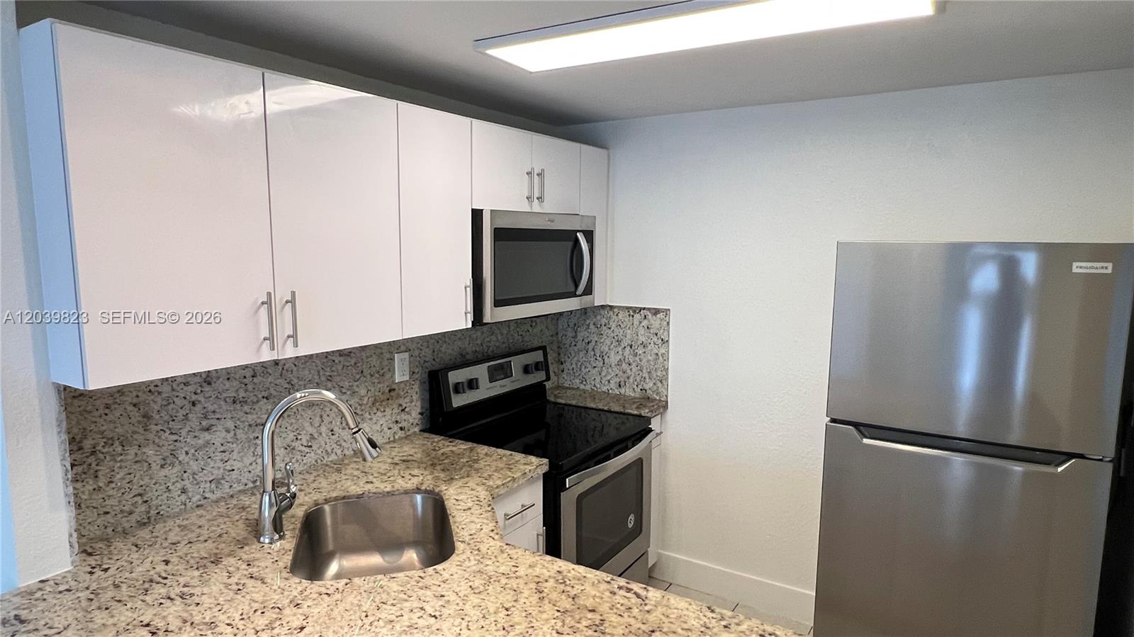 A kitchen features white cabinets, granite countertops, a stainless steel sink, and stainless steel appliances — 4550 NW 9th St # 817E, Miami FL 33126, MIAMI, FL