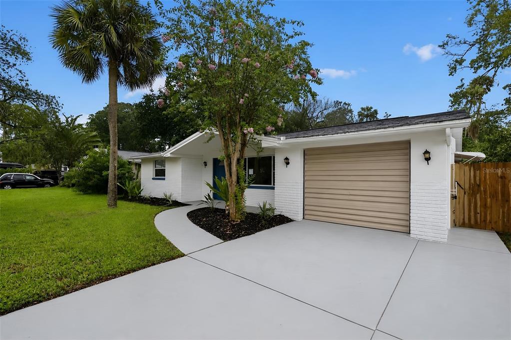 A white brick house with a tan garage door and a curved concrete driveway — 5644 BERLIN DRIVE, PORT RICHEY, FL