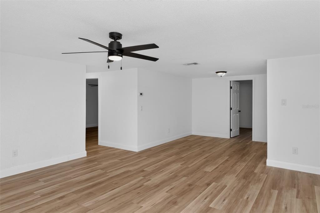 An empty room features white walls, a black ceiling fan, and light wood-look flooring — 5644 BERLIN DRIVE, PORT RICHEY, FL