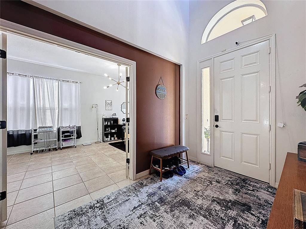 An entryway features a white front door, a tiled floor, and a doorway to a room — 344 ORANGE COSMOS BOULEVARD, DAVENPORT, FL
