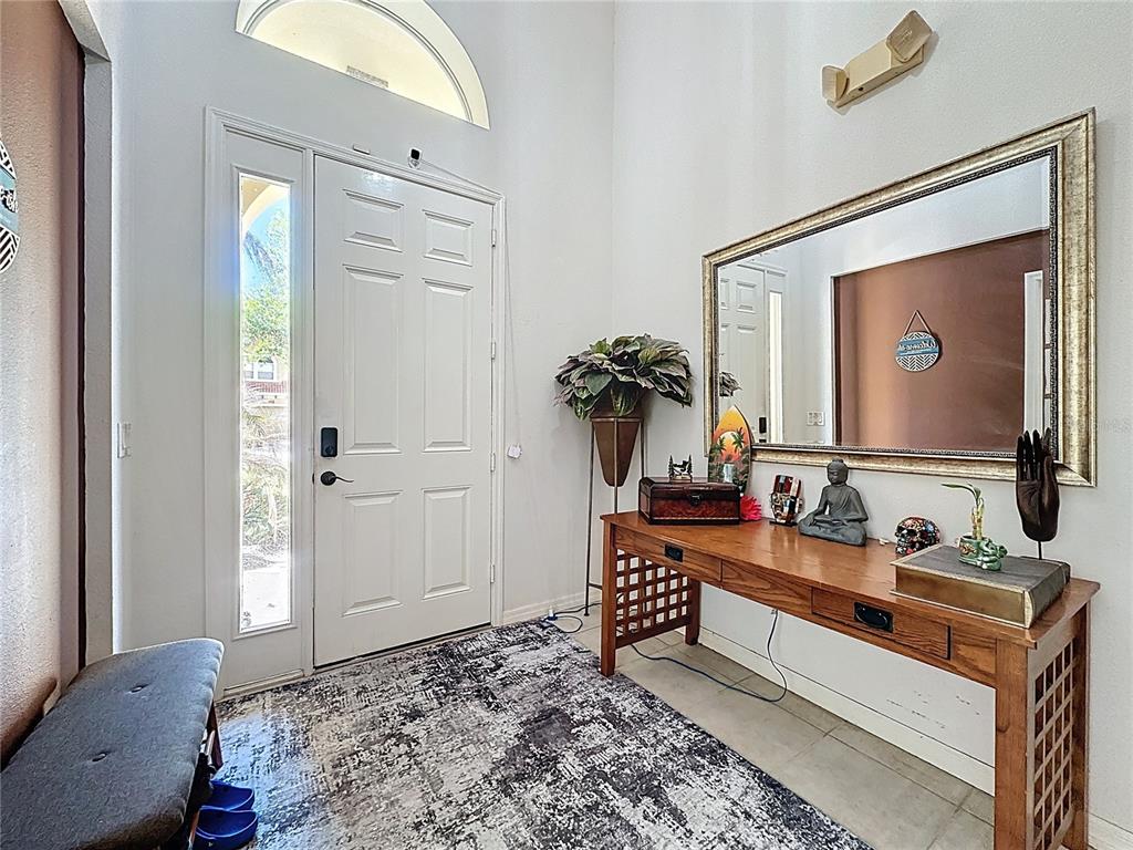 An entryway features a white front door, a wooden console table, and a large wall mirror — 344 ORANGE COSMOS BOULEVARD, DAVENPORT, FL