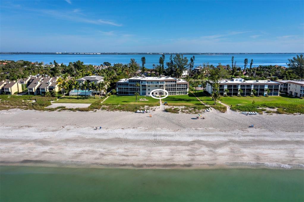 An aerial view shows a beachfront condominium complex with a circled ground-floor unit — 5231 GULF OF MEXICO DRIVE UNIT 104, LONGBOAT KEY, FL