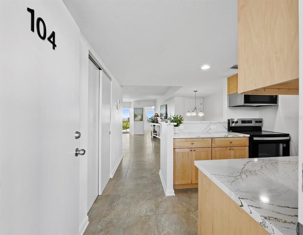 A view from an entryway looking toward a kitchen with light wood cabinets and countertops — 5231 GULF OF MEXICO DRIVE UNIT 104, LONGBOAT KEY, FL