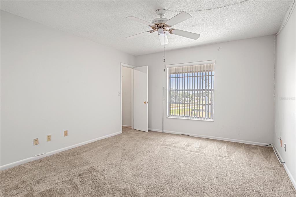 An empty bedroom features beige carpet, white walls, a ceiling fan, and a single window — 725 PORT MALABAR BOULEVARD NE UNIT 301, PALM BAY, FL