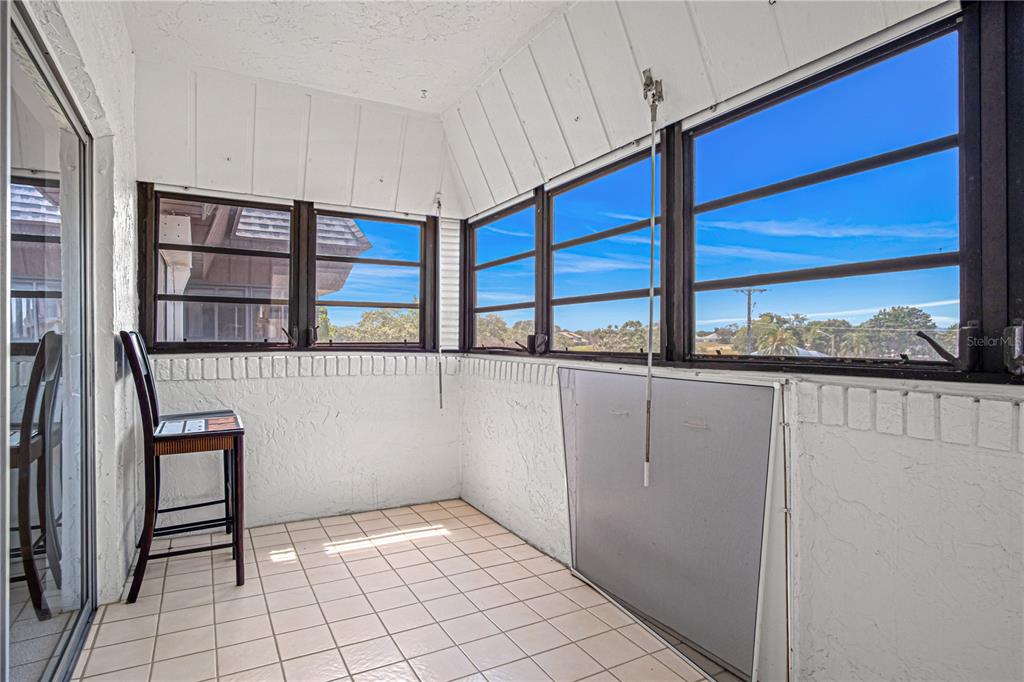A sunroom with white tiled flooring, white brick walls, and large windows overlooking the outdoors — 725 PORT MALABAR BOULEVARD NE UNIT 301, PALM BAY, FL