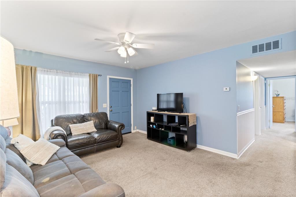 A living room features light blue walls, gray carpeting, a ceiling fan, and a blue door — 3014 VENICE WAY, LAKELAND, FL