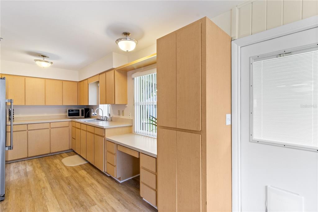 A kitchen features light wood cabinets, laminate countertops, and a built-in desk area — 3014 VENICE WAY, LAKELAND, FL