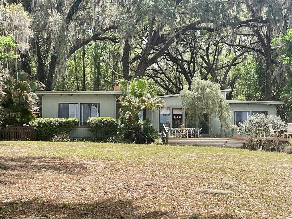 A single-story house with light green siding sits in a yard under large oak trees — 1800 SW 35TH PLACE, GAINESVILLE, FL