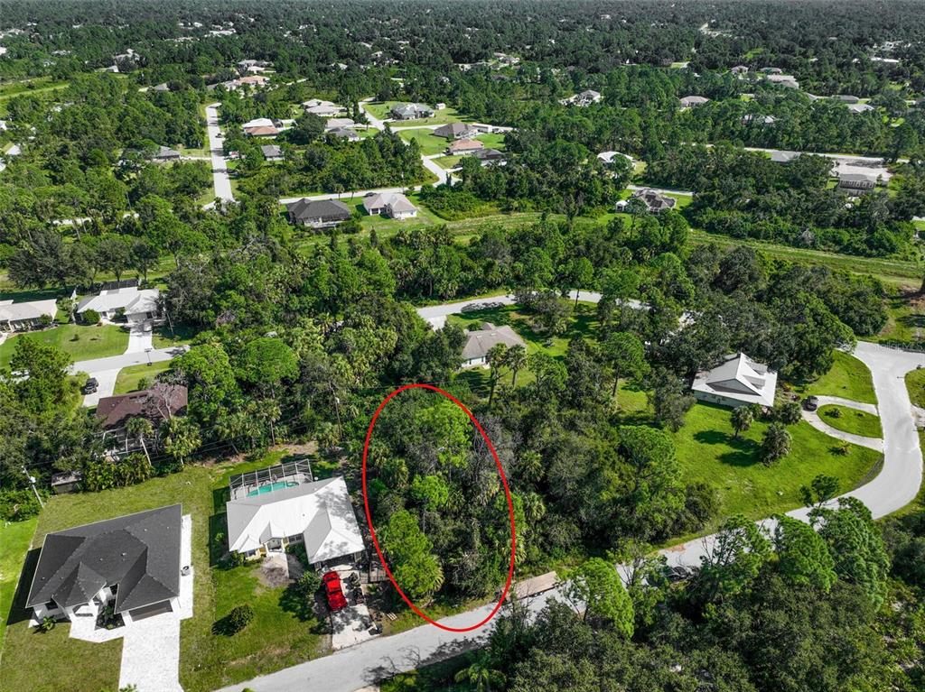 An aerial view shows a vacant, wooded residential lot circled in red within a neighborhood — RABBITT AVENUE, NORTH PORT, FL