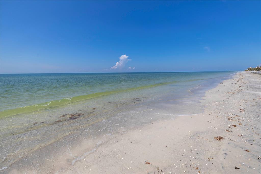 A view of a sandy beach meeting the calm ocean under a clear blue sky — 116 145TH AVENUE E, MADEIRA BEACH, FL
