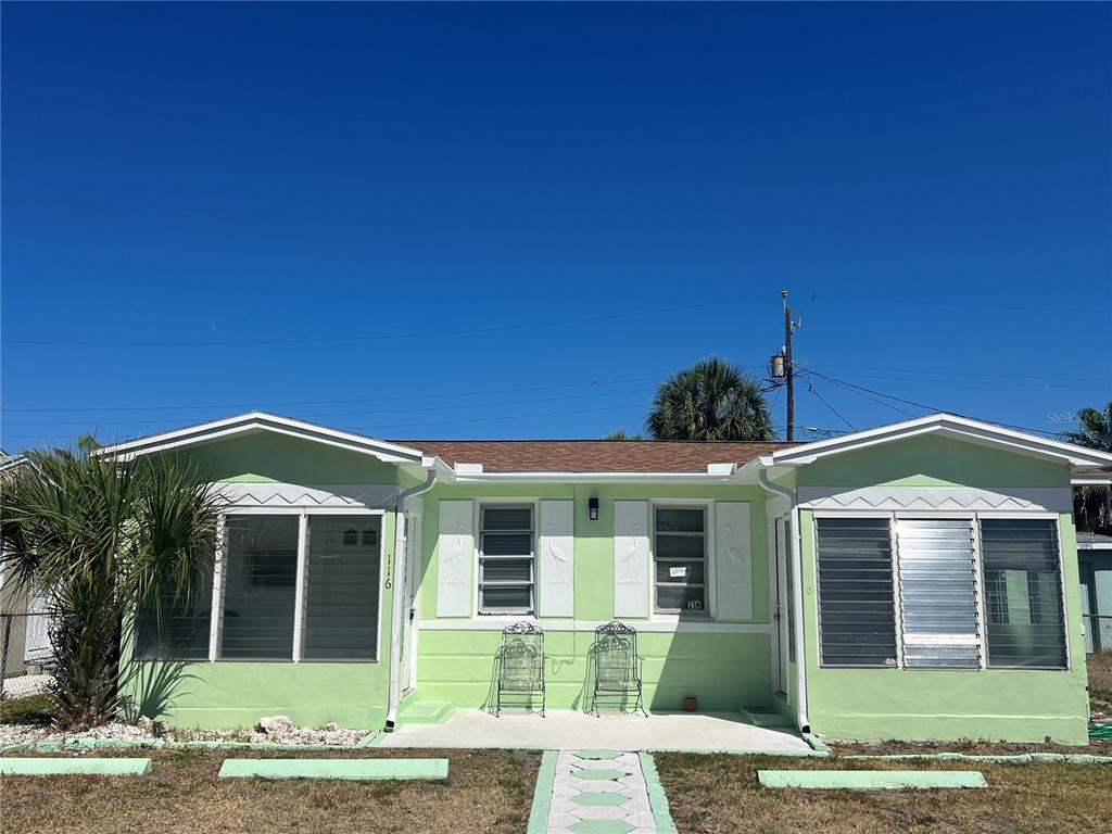 A light green single-story house with a flat roof and two sets of jalousie windows — 116 145TH AVENUE E, MADEIRA BEACH, FL