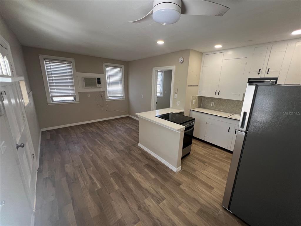 A kitchen with white cabinets, a stainless steel refrigerator, and wood-look flooring — 116 145TH AVENUE E, MADEIRA BEACH, FL