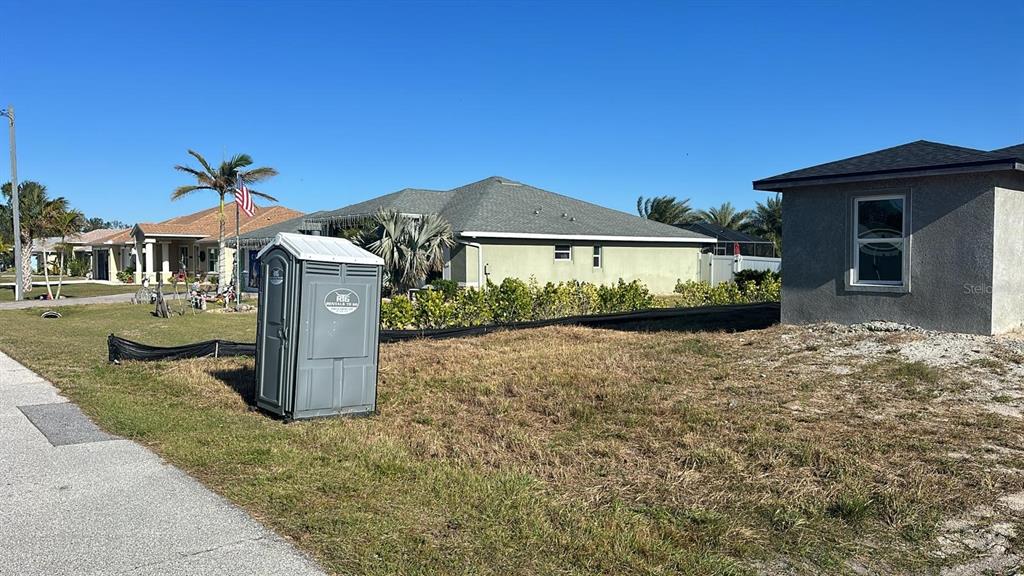 A portable toilet sits on a grassy lot next to a new house under construction — 13009 RIDGELY CIRCLE, PORT CHARLOTTE, FL